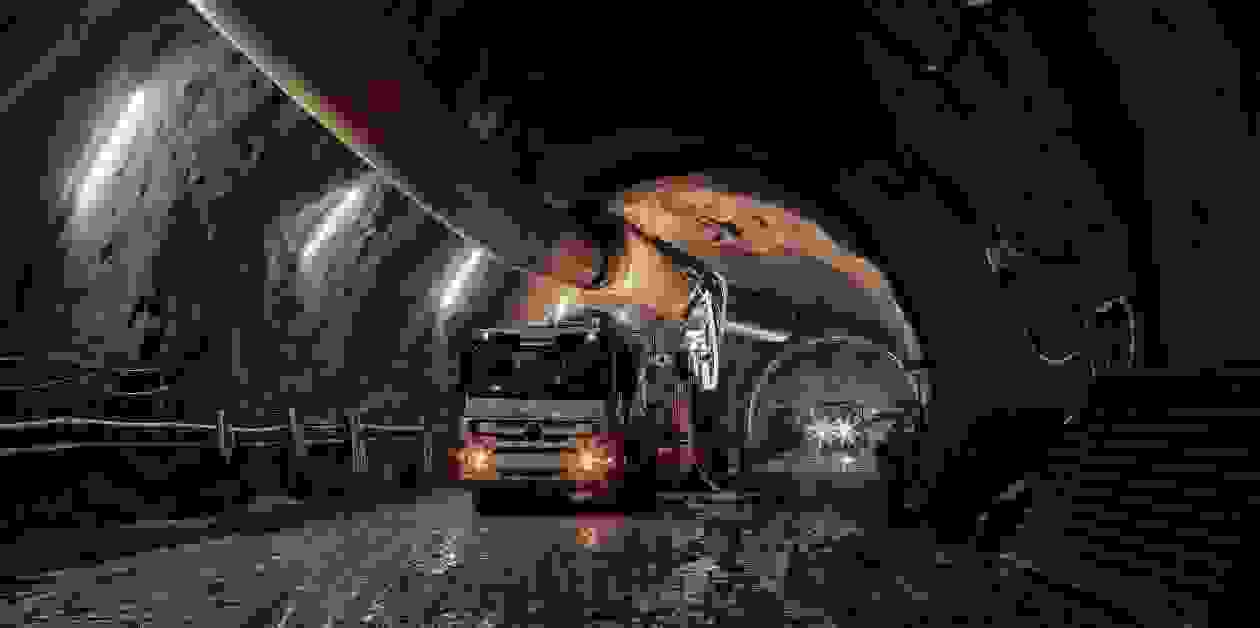 Construction vehicles inside a tunnel with a large pipe overhead