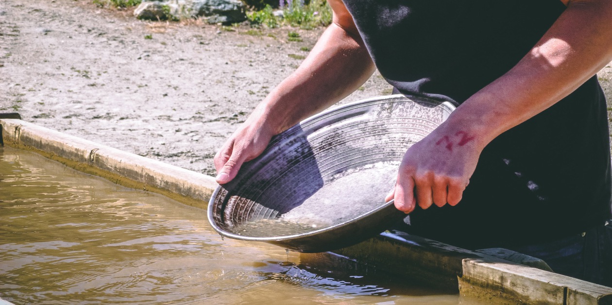 A person holding a sifter next to water