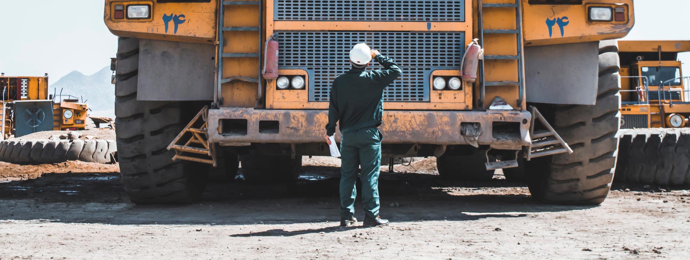 Construction worker looking at large vehicles at a mine
