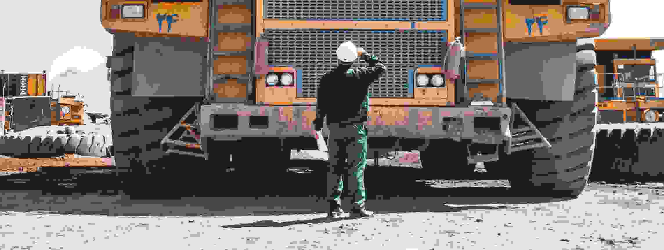 Construction worker looking at large vehicles at a mine