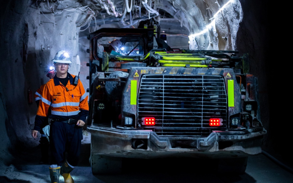 Workers inside a mine next to large machines and equipment for mining