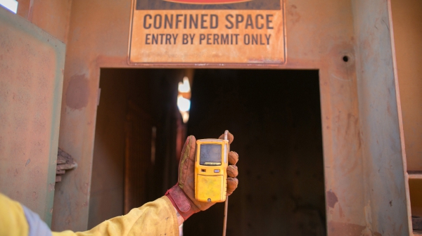 A man holding a piece of hand-held equipment at the entrance of a hole