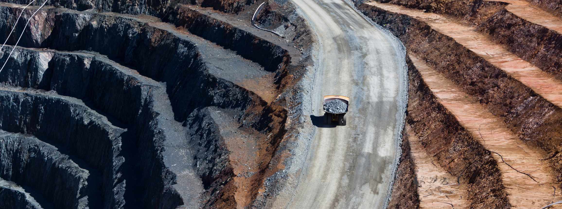 Construction worker at an extraction site surrounded by large vehicles